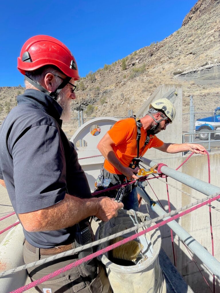 technicians lowering ropes into spillway